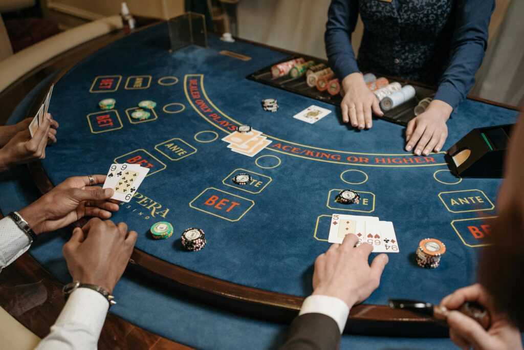 People playing a lively card game at a casino table with chips and a dealer.
